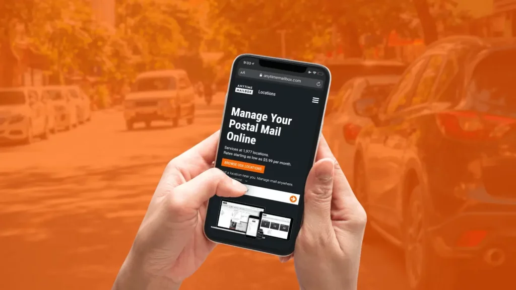 Person using a phone while on a road, with the Anytime Mailbox homepage on screen. 