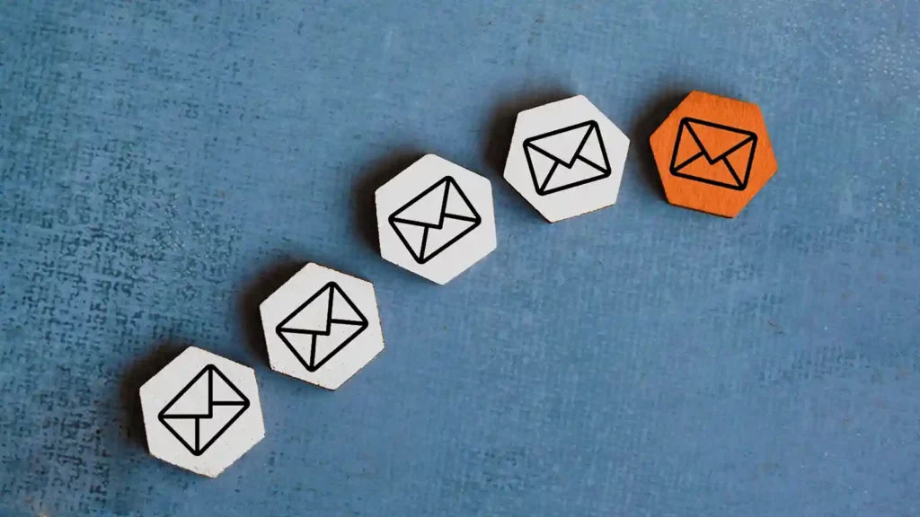 Hexagonal button pieces in a curved line and emblazoned with envelope icons. One button is orange while four are white.