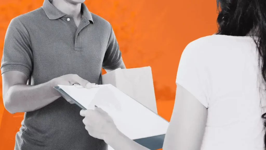 Man handing over a clipboard to a woman. The man is carrying a box.