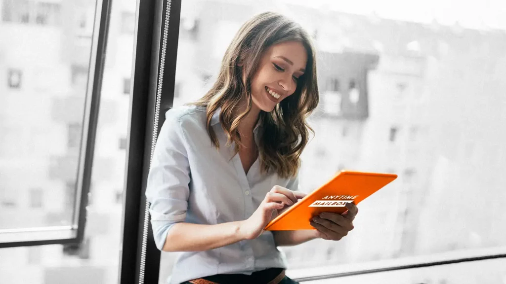 Smiling woman holding a tablet with an Anytime Mailbox label.