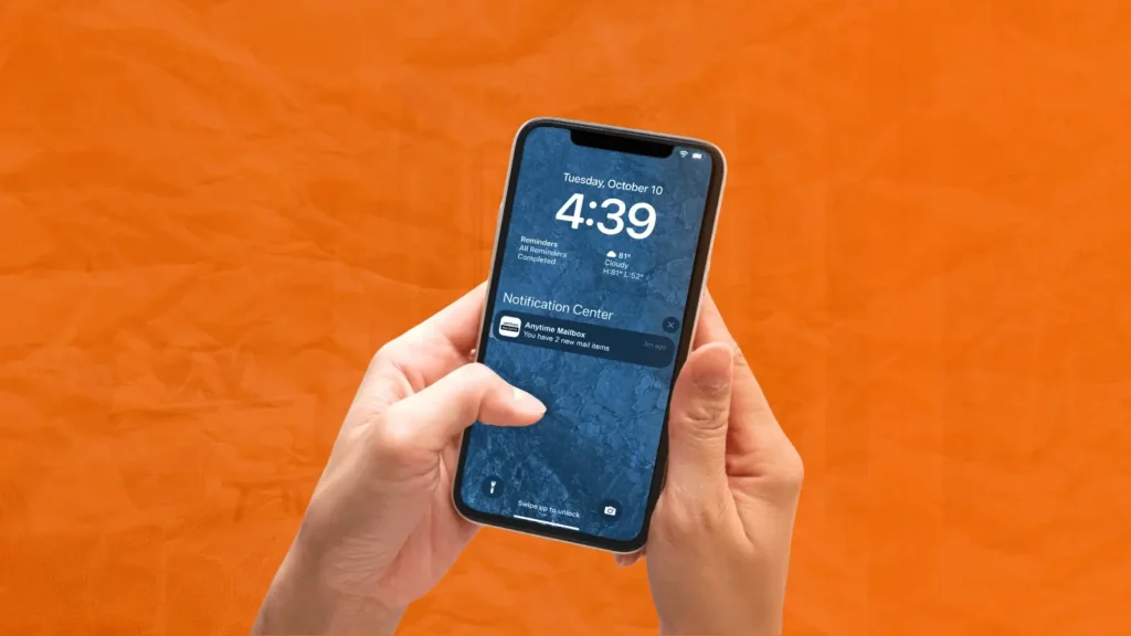 A pair of hands holding a mobile phone with a virtual mailbox notification