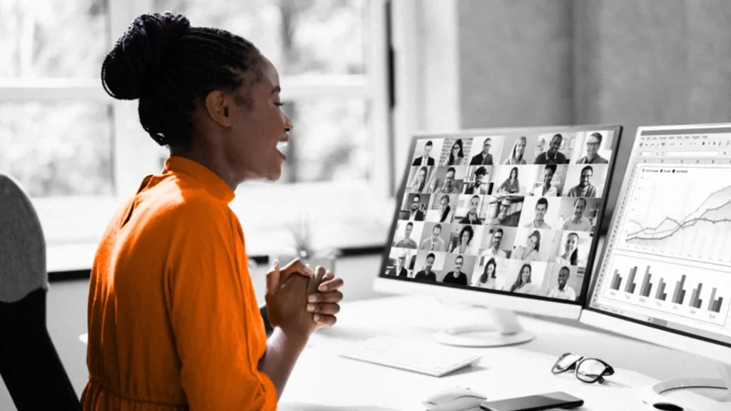 Woman in a video call, with two computer screens in front of her.